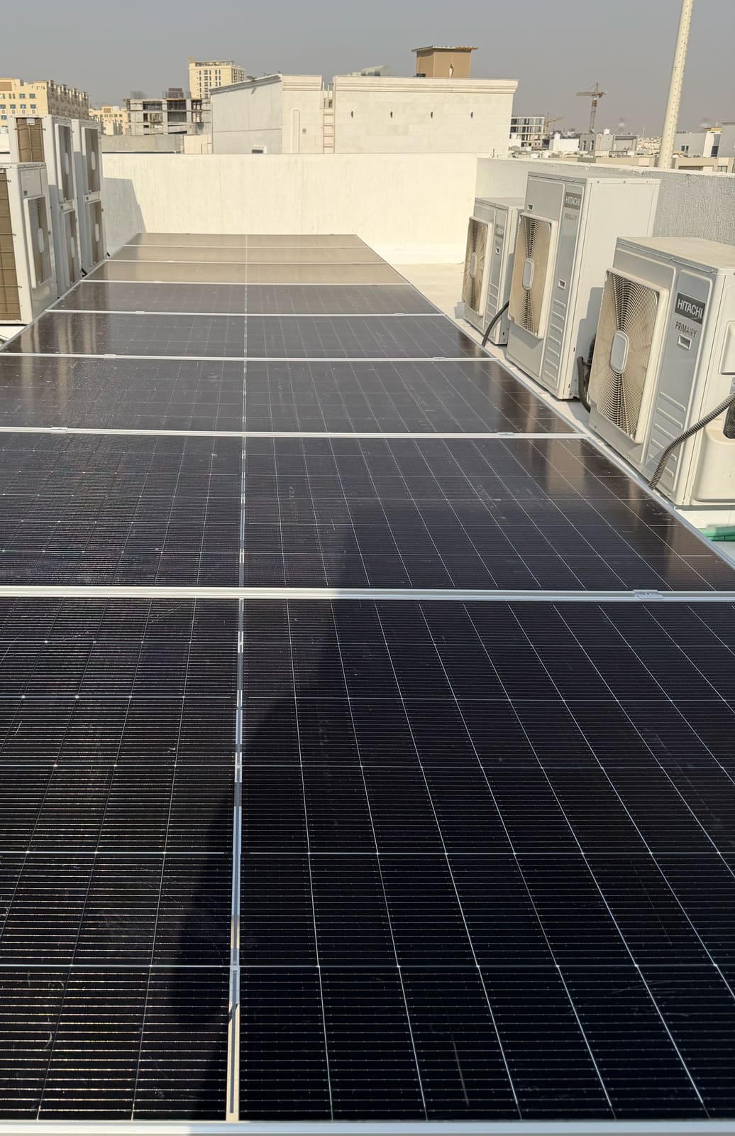 Solar panels in a row between air-conditioning units on a villa roof, Ajman