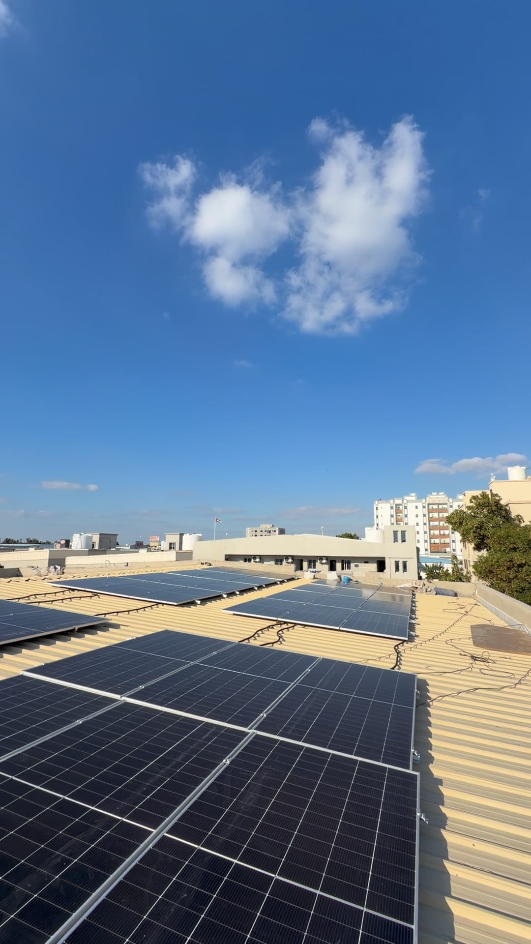 Solar panels on a metal roof under a deep blue sky with white clouds, Al Jurf, Ajman