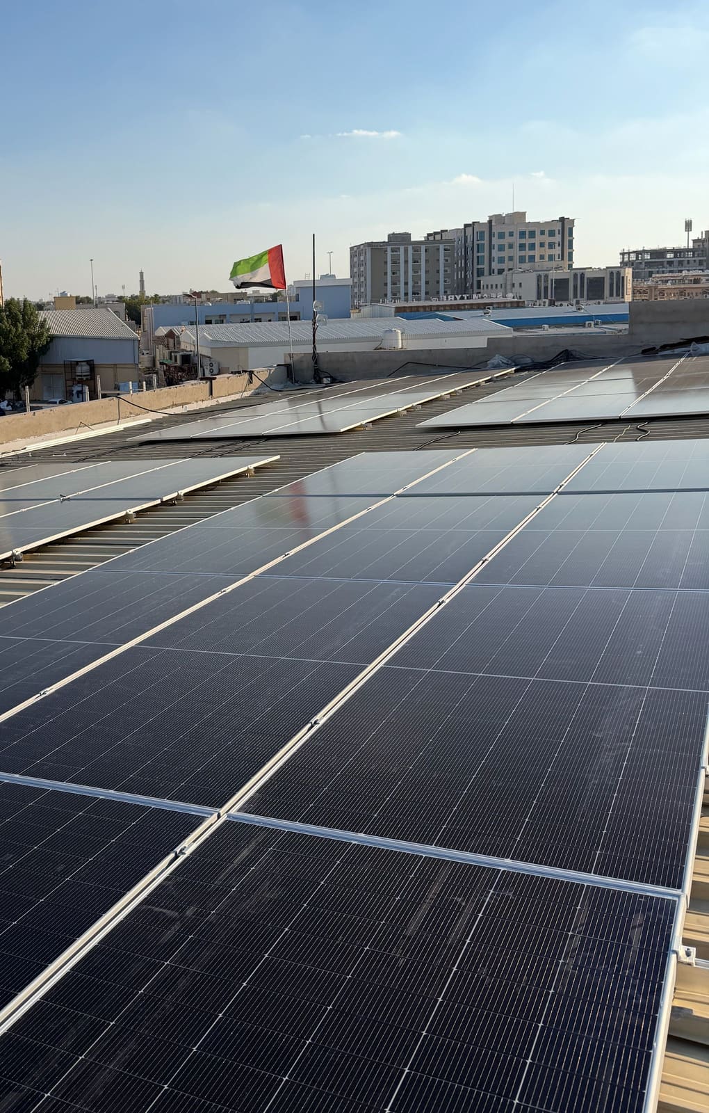 Finished solar array on a metal roof with the UAE flag flying behind it, Al Jurf, Ajman