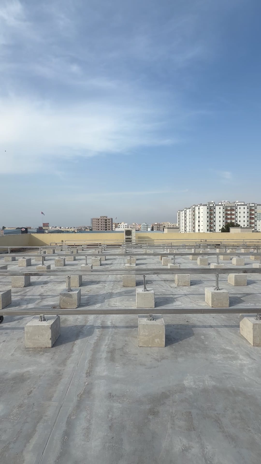 Ballast blocks and mounting rails laid out on a flat roof before the panels go on, Al Jurf, Ajman