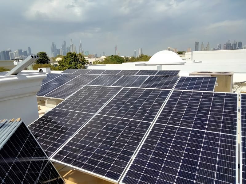 Solar panels on a villa roof in Emirates Hills, Dubai, with the city skyline in the distance